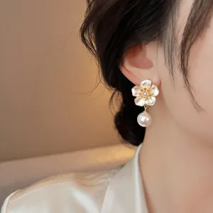 Detail view of French retro floral pearl drop earrings worn by a model on her ear.