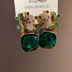 Detail of panda earrings with green gemstone pendants and crystal embellishments