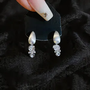 Detail view of silver drop earrings with faceted zircon stones on black background