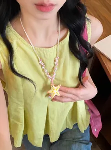 Close-up of a colorful starfish beaded necklace worn on a beach vacation style outfit