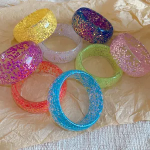 Detailed macro view of multiple colorful shimmering resin bangles on textured paper