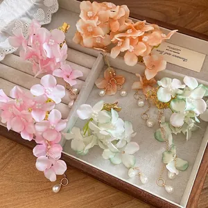 Handmade fabric flower hair clips with pearl tassels displayed in a jewelry box