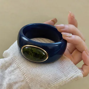 Macro detail of a chunky blue acrylic bangle with green marbled stone inset