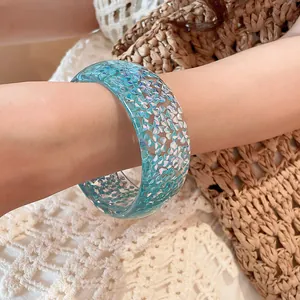 Detailed macro view of a blue translucent resin bangle with sparkling glitter inclusions.