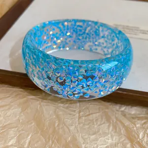 Close-up of blue resin bangle with iridescent holographic flakes and smooth finish