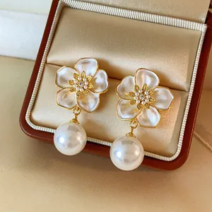 Close-up of French retro flower earrings with drip oil petals and dangling pearls.