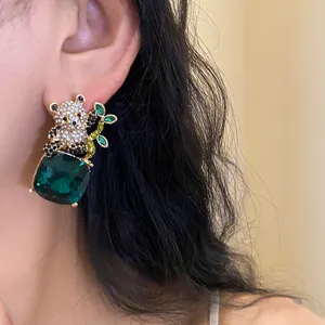 Close-up detail of panda stud earrings with a green square gemstone and rhinestones