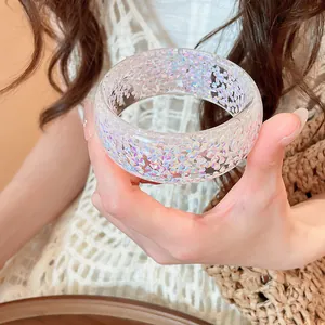 Close-up of transparent resin bangle with colorful iridescent heart-shaped glitter