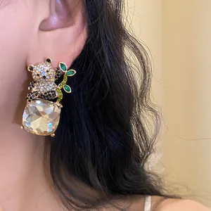 Close-up of a crystal-encrusted panda earring with a large square clear pendant