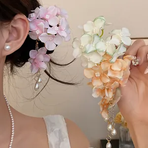 Detail of fabric flower hair clip with elegant pearl tassels worn by a model.
