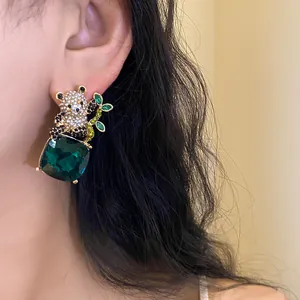 Detailed view of a panda stud earring with a large green square crystal pendant