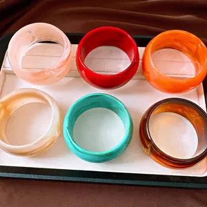 Set of colorful marble pattern acrylic resin wide bangles in a display tray.