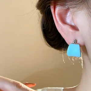Vue rapprochée d'une boucle d'oreille en émail bleu clair en forme de U sur une femme