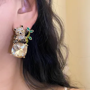 Detailed close-up view of silver needle panda earrings with a large square crystal