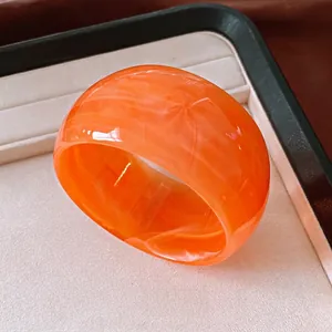 Vibrant orange marbled resin bangle with a wide geometric design for modern fashion styling