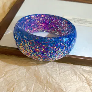 Detailed macro shot of an iridescent blue resin bangle with colorful glitter flakes