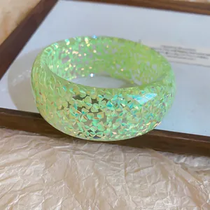 Detailed macro view of a light green resin bangle featuring iridescent shimmer flakes