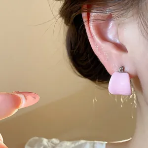 Gros plan détaillé de boucles d'oreilles créoles roses en émail portées à l'oreille