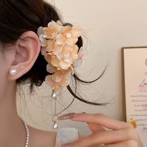 Close-up of a sweet fabric flower hair clip with pearl tassels worn on a woman's hair