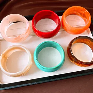 Detailed macro shot of six colorful marbled acrylic resin chunky bangles displayed in a tray.