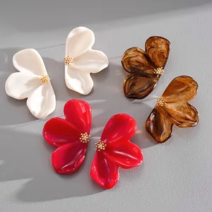 Macro shot of resin flower stud earrings in white, amber, and red with gold centers
