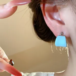 Gros plan de boucles d'oreilles créoles en U en émail bleu clair portées par un mannequin