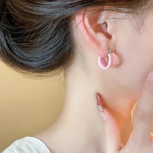 Détail d'un mannequin portant une boucle d'oreille créole rose en émail en U