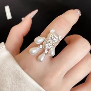 Detailed macro shot of an elegant zircon and pearl bear ring worn on a female hand