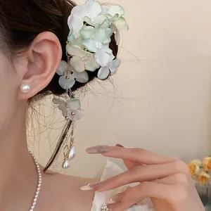 Detail shot of a white fabric floral hair clip with elegant pearl tassels worn by a model