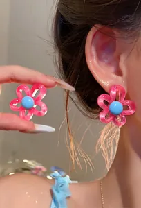 Detailed close-up of sweet pink and blue resin flower stud earrings worn on a model's ear