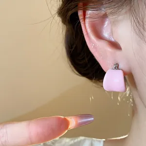 Gros plan détaillé d'une boucle d'oreille en émail rose en forme de U sur l'oreille