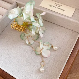 Detail of elegant fabric floral hair clip with pearl tassels and golden filigree base.