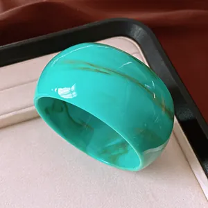 Detailed view of a wide marbled turquoise acrylic resin bangle with glossy finish