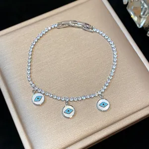 Close-up detail of a silver-toned zircon tennis bracelet with blue evil eye charms