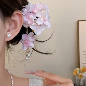 Detail shot of a pink fabric flower hair clip with elegant pearl tassels on a model