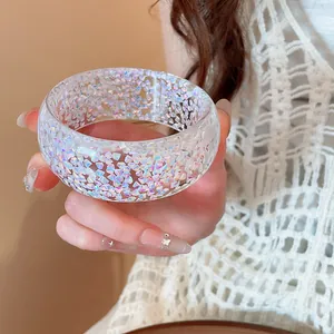 Detailed close-up of a transparent resin bangle with colorful iridescent flakes