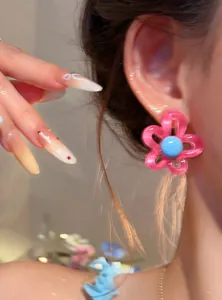 Macro detail shot of sweet pink resin flower stud earrings worn on a model's ear