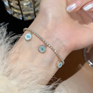 Close-up of 18k gold plated zircon bracelet with three blue evil eye charms on wrist