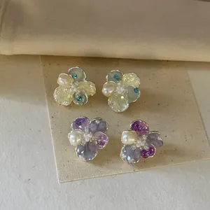 Close-up detail of delicate crystal pearl flower earrings in soft green and purple tones