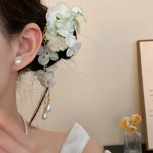 Elegant detail of fabric flower hair clip featuring delicate pearl tassels worn by a model