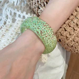 Light green resin bangle bracelet with shimmery triangle glitter on a female wrist.