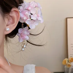 Close-up of sweet pink fabric flower hair clip with elegant pearl tassel on model.