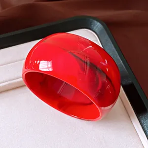 Detail of wide red resin bangle with black marbled texture and high-gloss finish