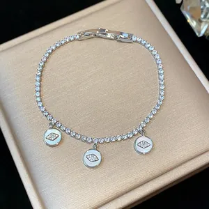 Macro view of a shimmering silver tennis bracelet featuring three zircon-studded eye charms