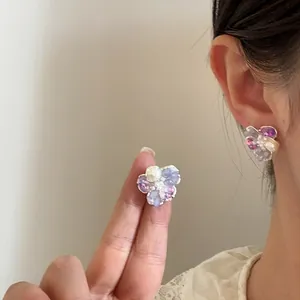 Detailed view of elegant flower stud earrings with purple crystals and central pearl