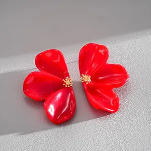 Detailed macro view of vibrant red resin flower stud earrings with golden floral centers
