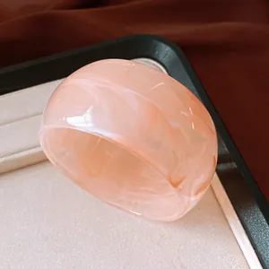 Close-up of a wide marbled pink resin bangle showing smooth texture and swirled patterns