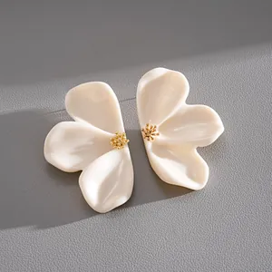 Close-up macro detail of elegant cream resin flower stud earrings with gold centers