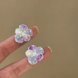 Close-up view of elegant ice-translucent crystal flower stud earrings with pearls.