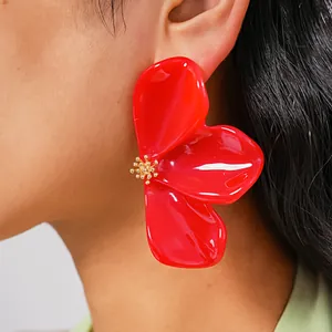 Macro close-up detail of oversized red marbled resin flower stud earring on model's ear